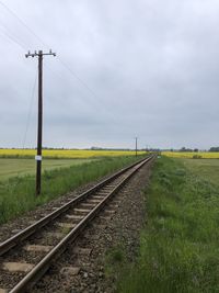 Railroad track amidst field against sky