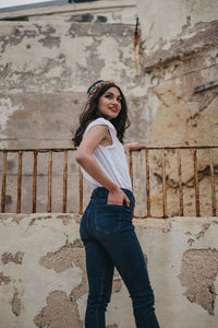 Portrait of smiling woman standing against wall