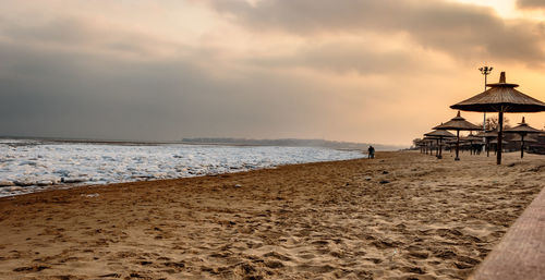 Lifeguard hut on beach against sky during sunset