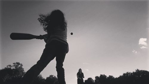 Low angle view of silhouette girl playing against sky