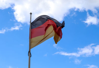 Spain flag at a flagpole moving in the wind against the sky