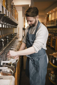 Mature owner filling food in scoop while working in store