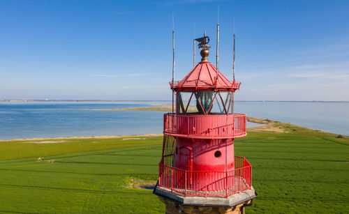 Lighthouse by sea against sky
