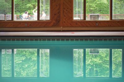 View of swimming pool seen through window of house