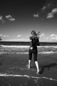 Low section of woman walking on beach against sky