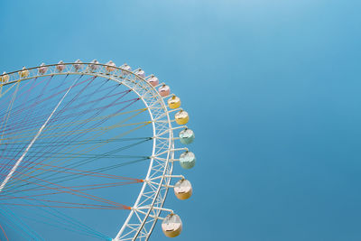 Low angle view of ferris wheel against blue sky