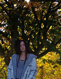 Portrait of young woman standing against trees