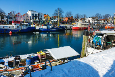 Boats moored at harbor against clear sky