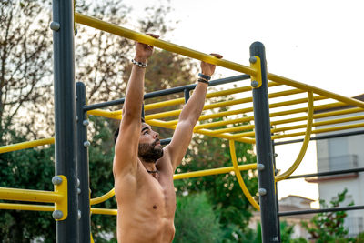 Shirtless man wearing mask exercising at park