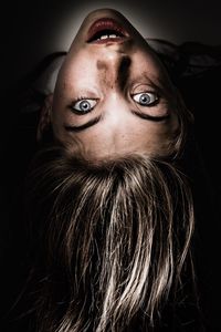 Close-up portrait of young woman against black background