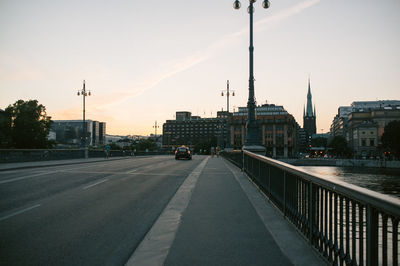 Road passing through city at sunset