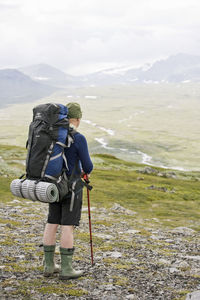 Rear view of mature man with backpacker standing on landscape