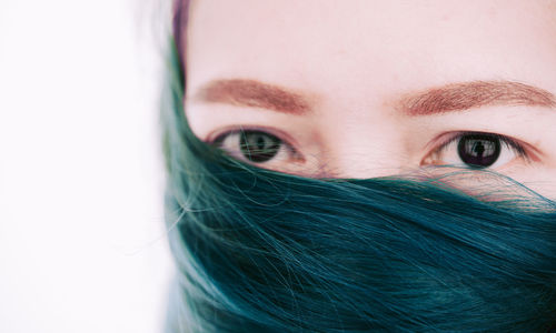 Close-up portrait of young woman with dyed hair against white background