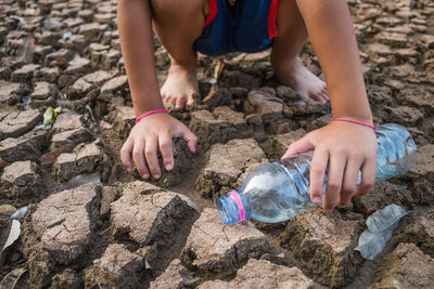 Low section of child standing bottle on barren field