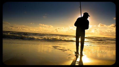People standing on beach at sunset