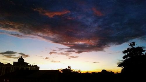 Low angle view of silhouette trees against dramatic sky