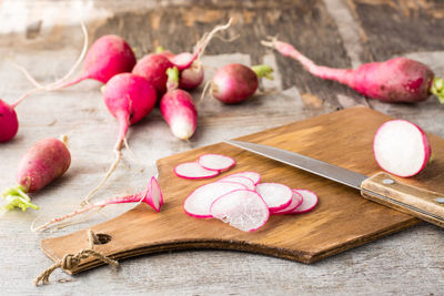 Fresh chopped radishes and a knife on a cutting board on a wooden table