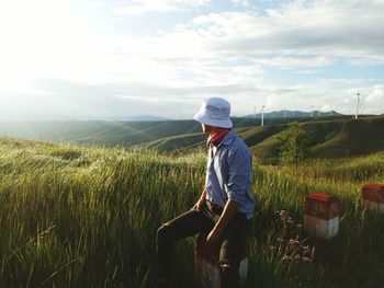 Man wearing hat on grassy field against sky