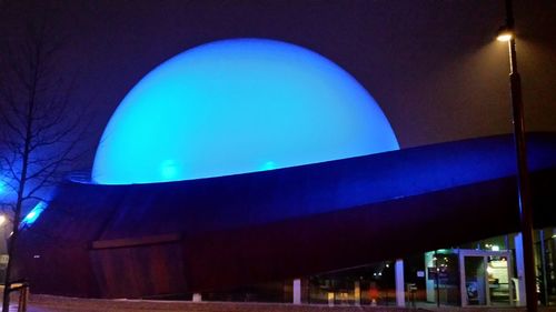 Low angle view of illuminated building against blue sky at night