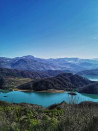 Scenic view of lake and mountains against clear blue sky