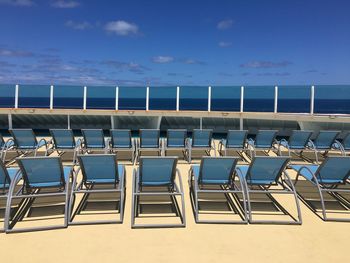 Empty chairs on beach against blue sky