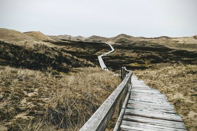 Boardwalk leading towards mountain against sky