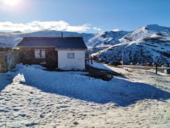 Snow covered houses by buildings against sky