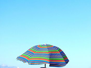 Low angle view of multi colored umbrella against clear blue sky
