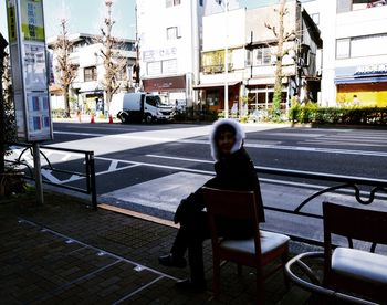 Full length of man sitting on street in city