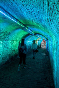 Rear view of people walking in tunnel