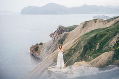 Rear view of woman standing by sea