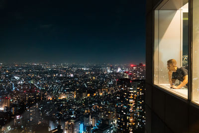 Man looking at city while standing by window