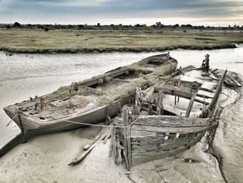 Abandoned boat on shore against sky