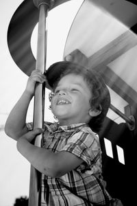 Low angle view of smiling boy hanging on pole at playground