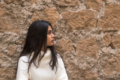 Young woman standing against wall