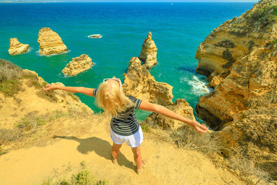 Woman with arms outstretched standing at beach