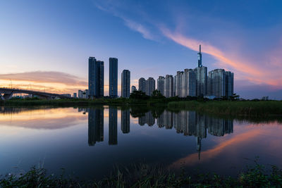 Reflection of buildings in lake against sky during sunset