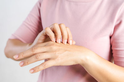 Close-up of woman holding hands over white background