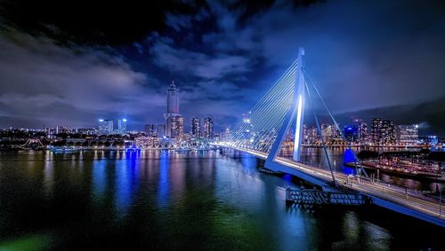 Illuminated bridge over river against sky in city at night