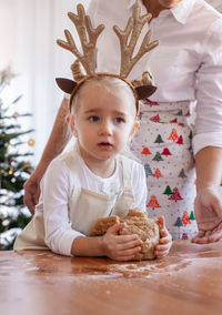 Portrait of cute girl playing with gingerbread cookies at home