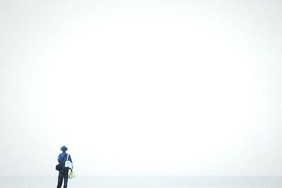 Rear view of man looking at sea against clear sky