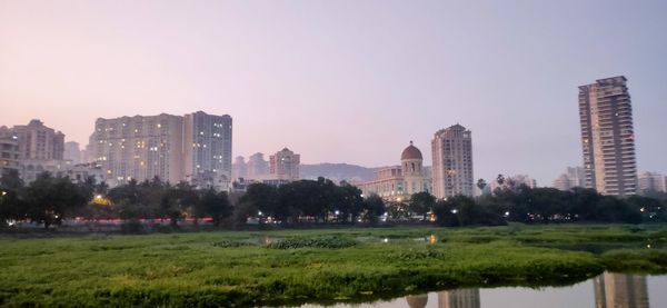 Buildings by lake against sky in city