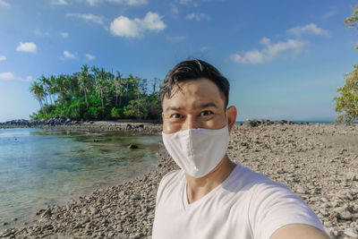 Man with face mask has a summer sea trip while in covid-19 pandemic.