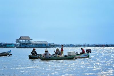 People boating in tonle sap lake against sky