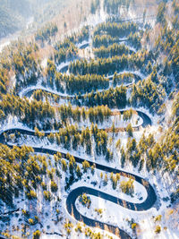 Winding road through the forest, from high mountain pass, in winter time. aerial view by drone