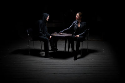 Young woman sitting on chair in dark room