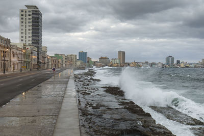 Sea by buildings in city against sky