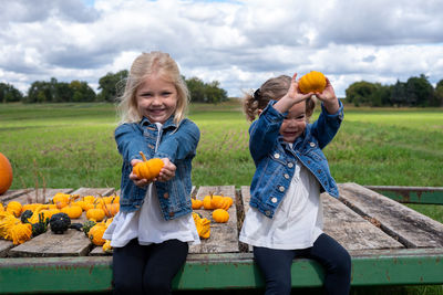 Full length of smiling girl holding pumpkin