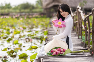 Portrait of beautiful vietnamese woman with traditional vietnam hat holding the pink lotus