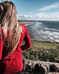 Rear view of woman standing by sea against sky